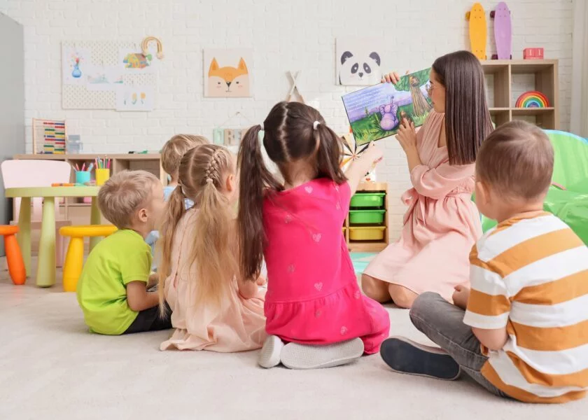 Nursery,Teacher,Reading,Story,To,Little,Children,In,Kindergarten,,Back